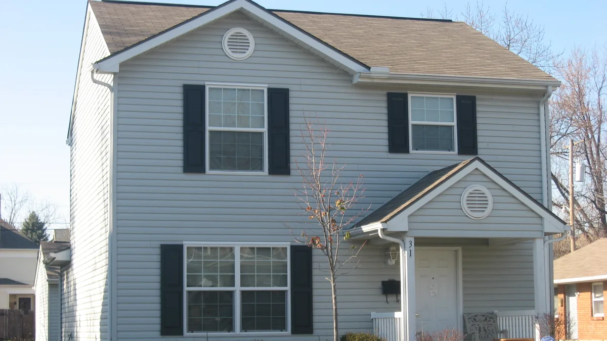 A modest grey vinyl-sided two-storey suburban home with black shutters in Dayton, Ohio